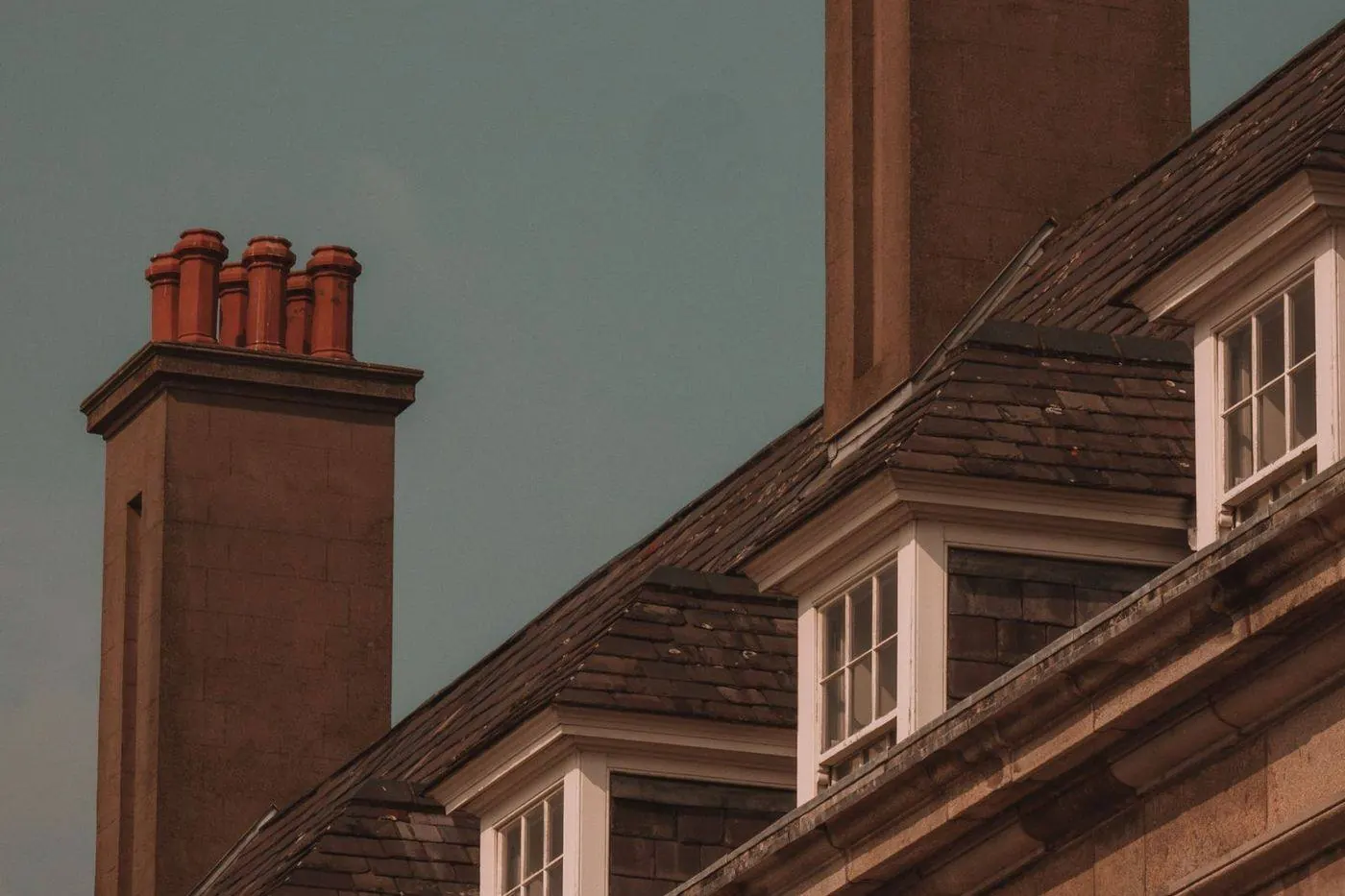 Close-up of metal step flashing where a brick chimney meets a shingle roof