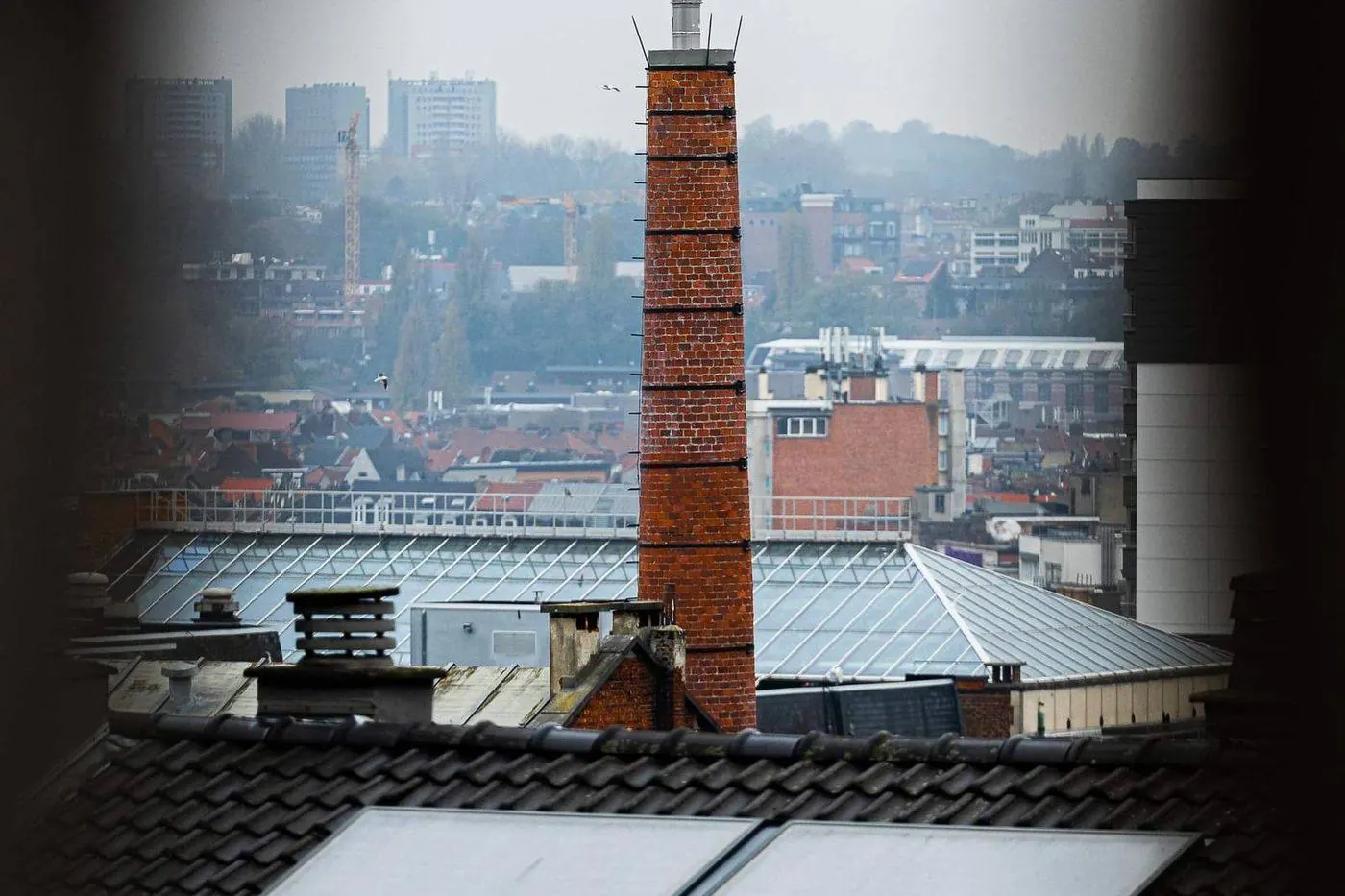 Brick chimney rising through a shingle roof with step flashing at its base