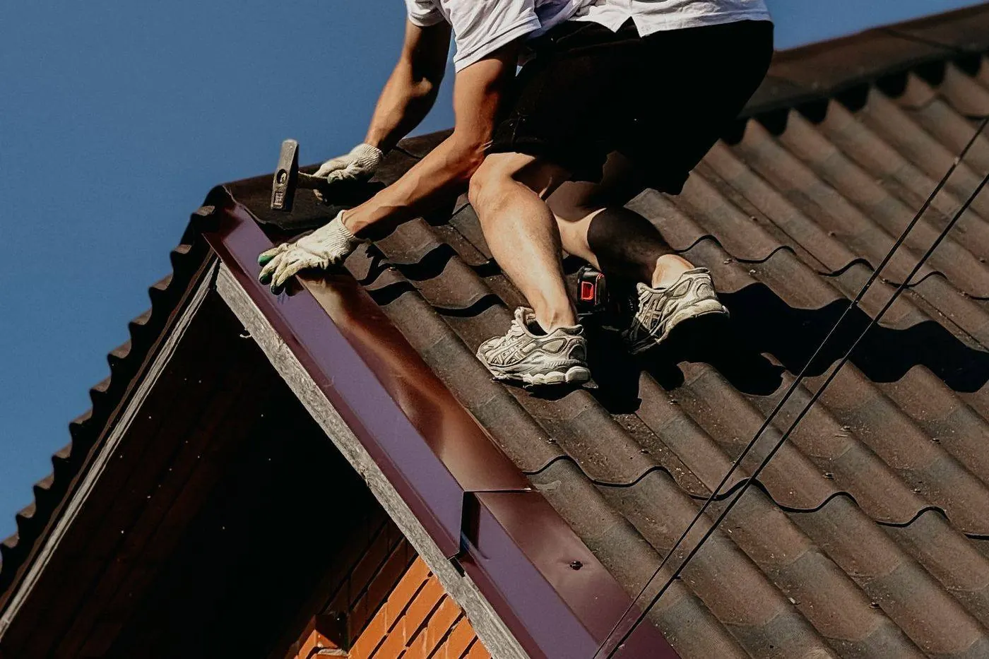 Roofer installing new metal step flashing around a chimney base