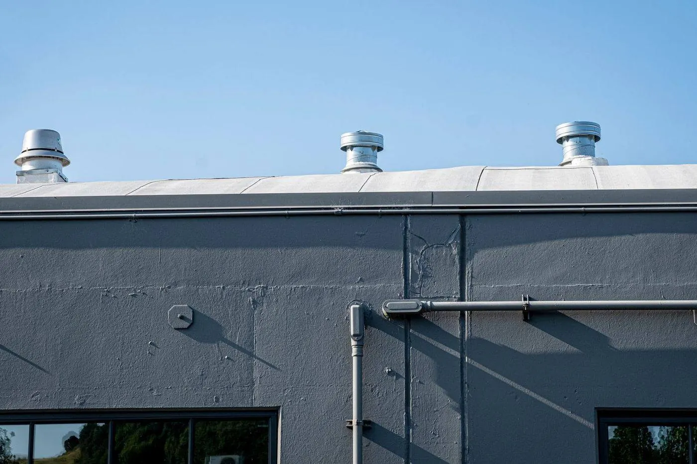 Flat membrane roof with rooftop HVAC unit, vent pipes and parapet walls