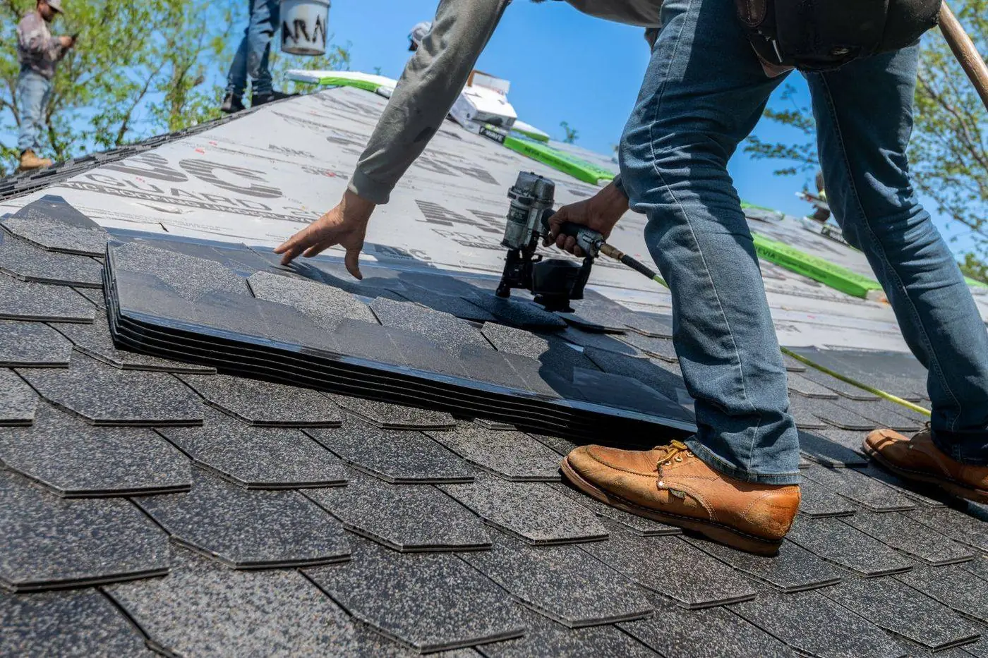 Roofer nailing a new asphalt shingle into place during repair